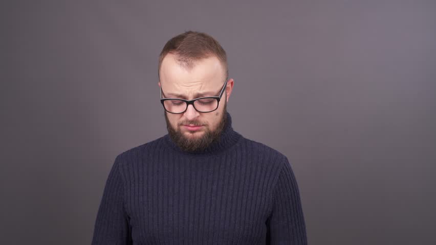 Portrait of a young bearded man in glasses, who asking for forgiveness. Feeling confused. Isolated on grey background. Royalty-Free Stock Footage #1020570490