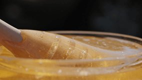 Useful honey dripping from the honey spoon, pick the spoon up, outdoors. Slow motion closeup video