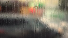 Urban street with blurred objects and raindrops on window glass