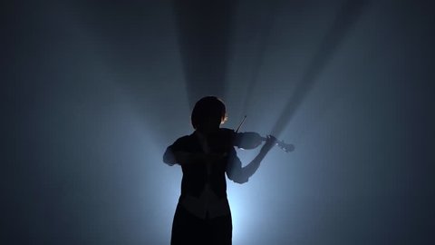 Violinist performs on a violin in a black smoke studio. Silhouette. Black smoke background