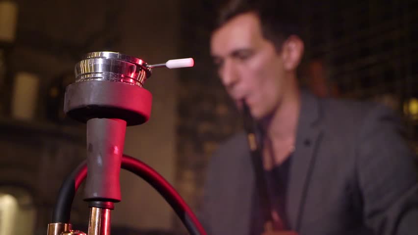 Hookah smoker. Young man smoking shisha or hookah in cafe or bar. Resting in shishabar lounge. Businessman working with laptop