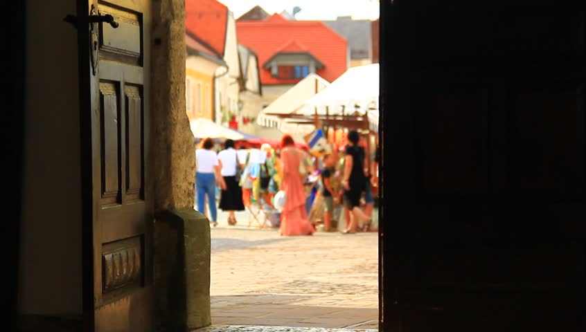Observing people on the street square through opened house doors. Street performance happening.