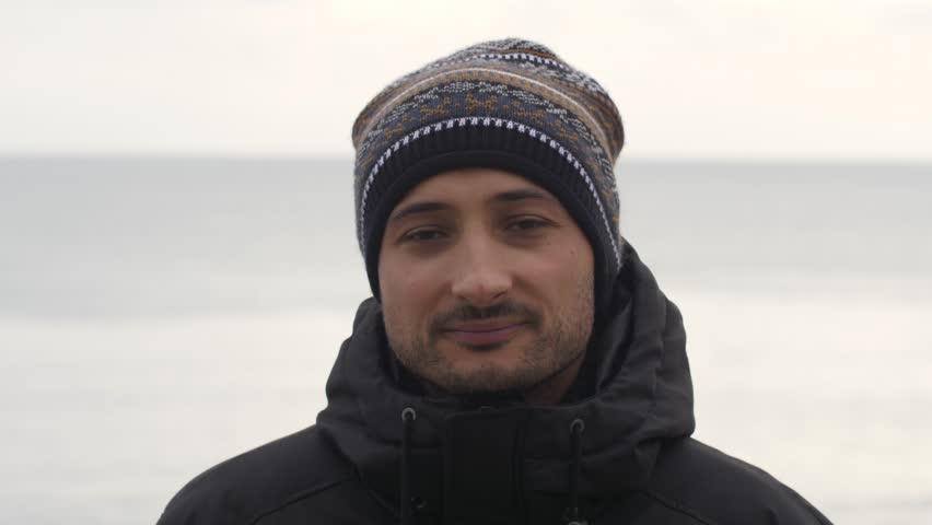 portrait of an attractive man in the background of the sea in winter
