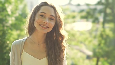 Beautiful young woman in casual looking camera and smiling in park