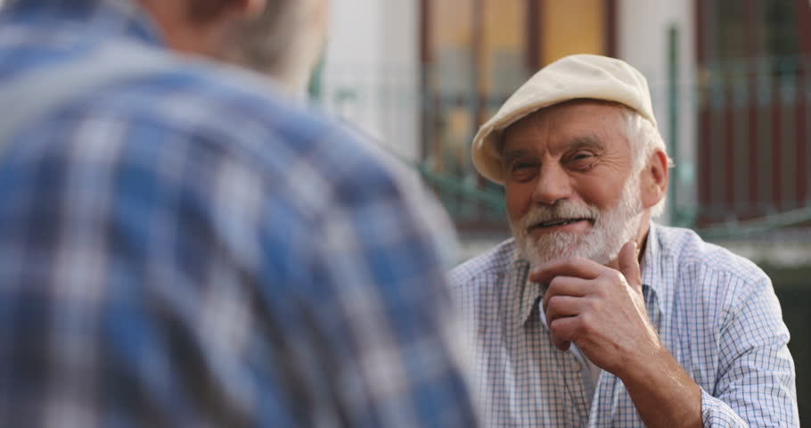 View over the shoulder on the Caucasian smiled old man in a cap talking cheerfully while playing with his best friend. Portrait. Rear. Outside. | Shutterstock HD Video #1020618784