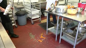 Kitchen worker cleans-up a mess on the floor.  A food safety and occupational health topic.