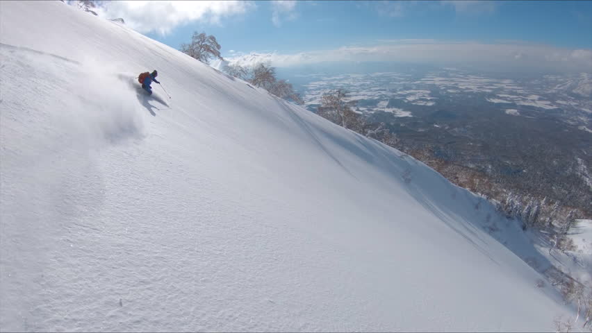 SLOW MOTION, DRONE: Awesome freestyle skier shredding the fresh snow while riding in the scenic mountains in Japan. Flying along the active male tourist skiing downhill in the breathtaking backcountry | Shutterstock HD Video #1020620551