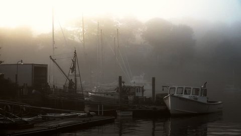ROCKPORT, MAINE circa July 2017 - Lobster fishing boat getting ready to set sail in the early morning light at sunrise in a foggy and quaint New England harbor.