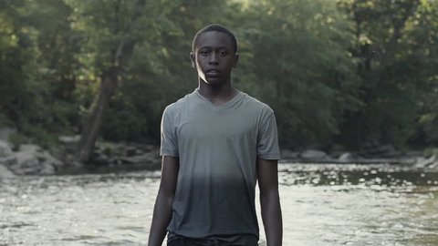An African American boy stands tall in aing river.