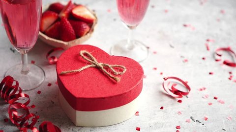 Bottle of rose champagne, two glasses with fresh ripe strawberries and heart shaped boxed gift, placed on stone table for a special romantic occasion or Valentines. With copy space