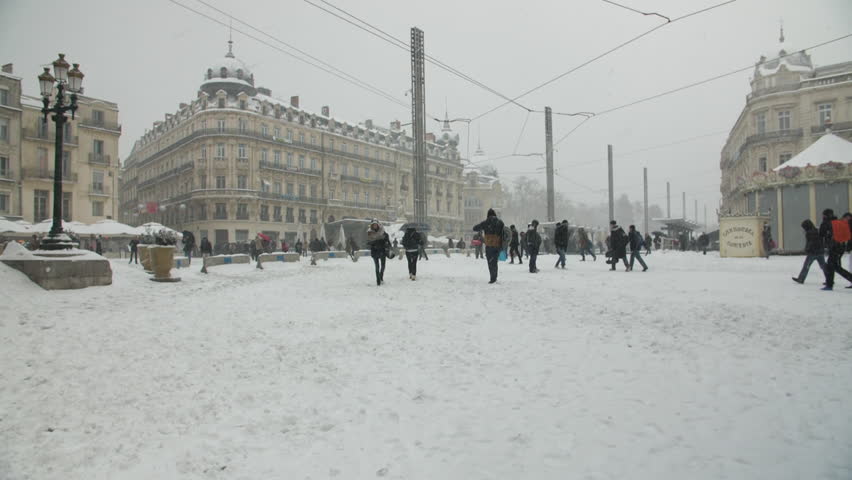 Snowy day Place de la Comedie square in Montpellier with people walking in slow motion. 