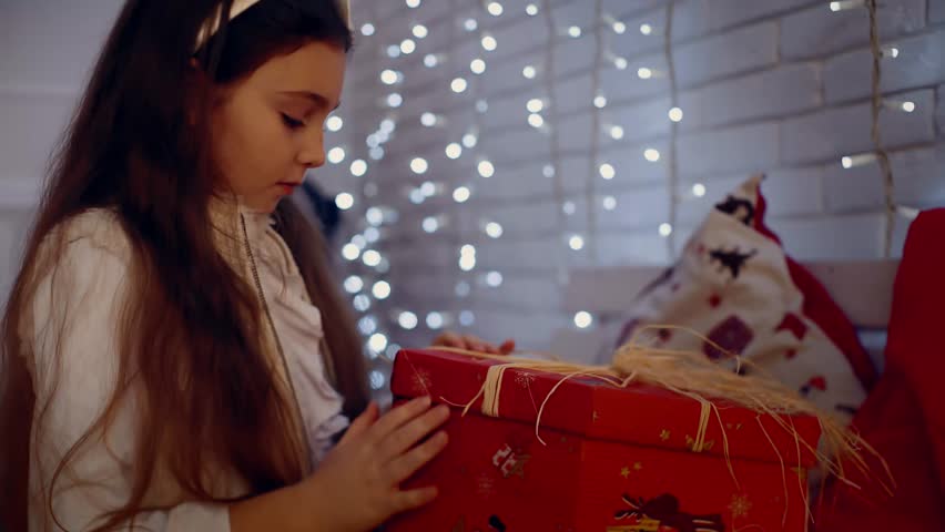 Extremely happy little girl glad about the christmas present . near a decorated Christmas tree