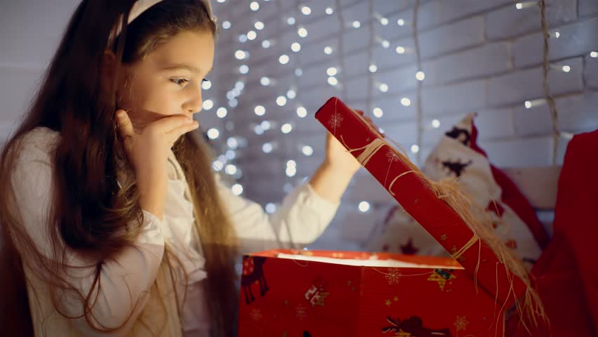Extremely happy little girl glad about the christmas present . near a decorated Christmas tree | Shutterstock HD Video #1020636487