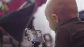Little boy is chatting on video call in a smartphone on tripod with his father. 4K slow mo