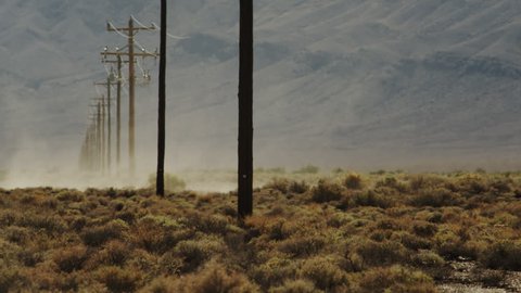 Dust devil roars through a row of power poles in the Mojave desert