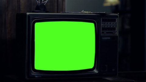 Old Vintage Television Set with Green Screen in a Room at Night. Zoom Out. 