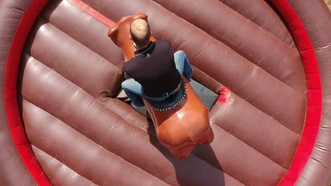Aerial view of a person riding an mechanical bull riding machine, drone footage