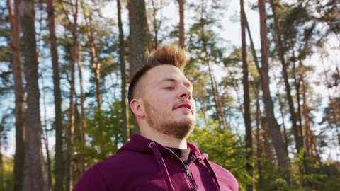 A young man stretching in the forest. Medium shot to close-up.