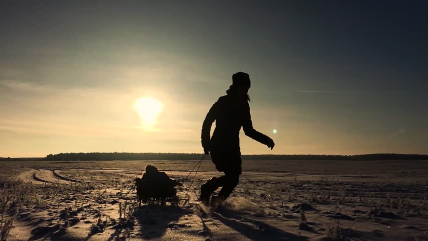 Little boy enjoying a sleigh ride. Mother sled his cute child. Family winter activities outdoors. Happy family having fun outdoor.