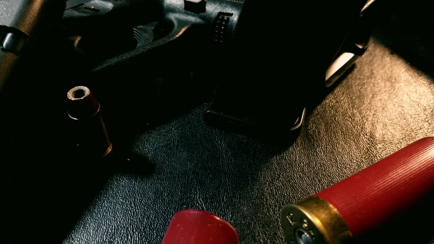 Tilting shot of shotgun shells, gun and magazines