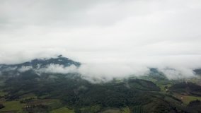 A panoramic rotational view high above the white fluffy scattered clouds looking down at farmland and rice crops in Chiang Rai Thailand