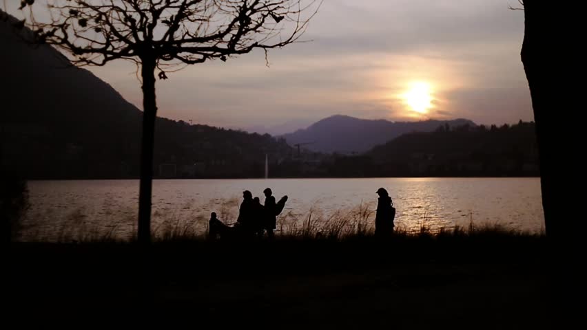 Lugano, Silhouette of people standing on shore against sky during sunset