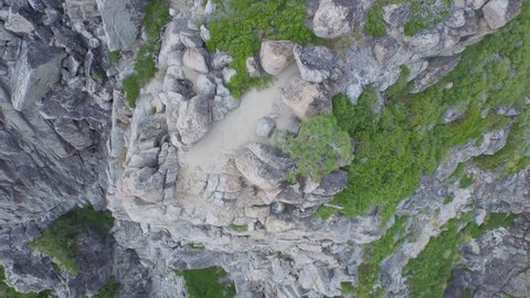 Aerial drone view of mountain rocks and cliff near Tahoe Lake in California. Pine tree forest below.