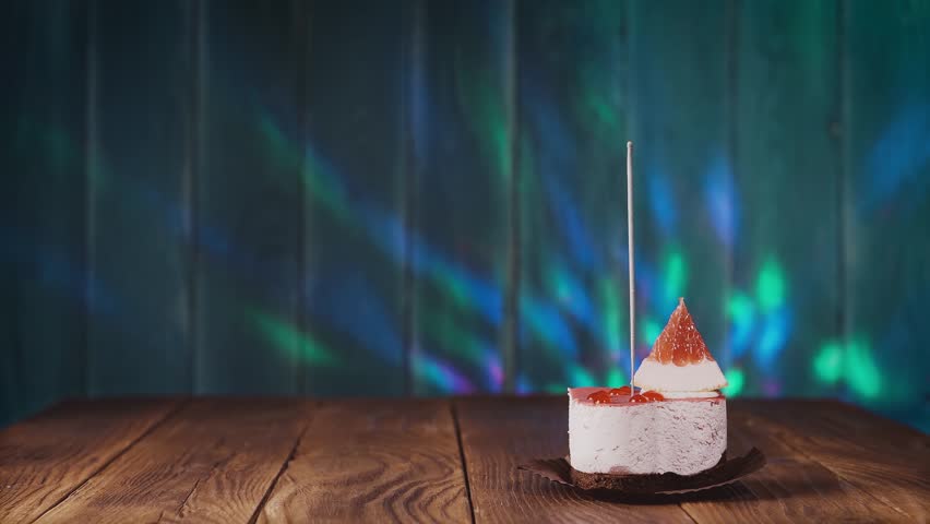 Delicious cupcake with bengal light on wooden background. Cupcake with sparkler. Female hand ignites the candle on the cake. 