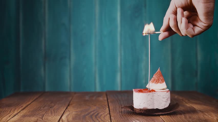 Delicious cupcake with bengal light on wooden background. Cupcake with sparkler. Female hand ignites the candle on the cake. 