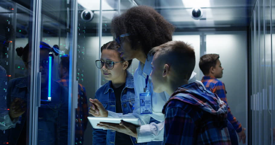 Medium shot of a young female technician showing around children in a server park