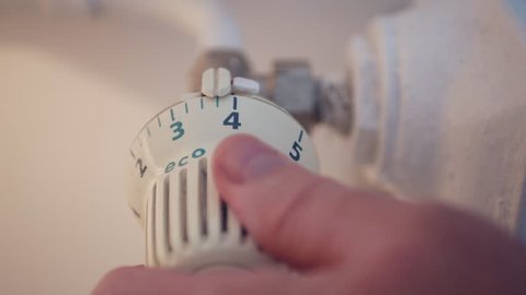 Man in Office Room Setting Radiator Temperature from Thermostat Saving Energy