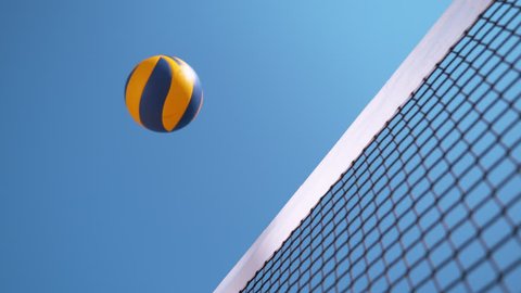 SLOW MOTION, CLOSE UP, LOW ANGLE: Unknown beach volleyball player smashes the ball past the blocker's arms and hands. Cool shot of unknown athletic people playing volleyball on a sunny summer day.