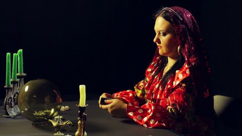 A young gypsy in a red dress at the table lights the candles. The average plan