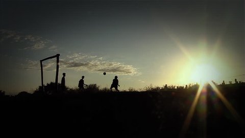 Silhouette of Three Young Men playing Soccer on Rural Landscape at Sunset, in Argentina, South America.