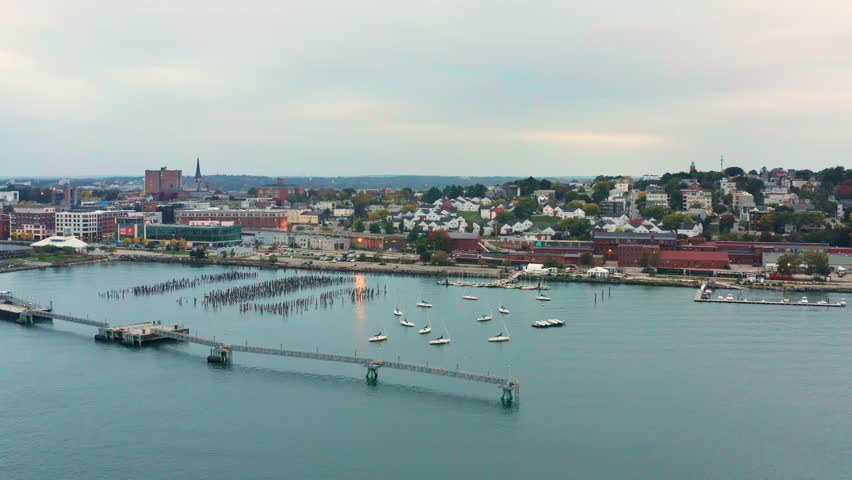 Aerial drone footage of the Portland, Maine waterfront, harbor, marina and skyline, at dusk (parallel panning)
