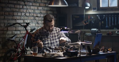 Medium shot of a man repairing and testing a drone in a garage
