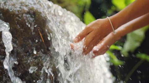 Female Hand Touching Fresh Clean Natural Spring Waterfall in Jungle Rainforest. 4K Slowmotion. Bali, Indonesia.