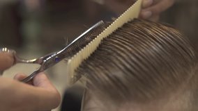 Hairstylist cutting wet male hair in with barber scissors in hairdressing salon. Hairdressing doing boy haircut with hair scissors in barber shop. Kid hairstyle concept