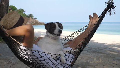 Girl Relaxing On Hammock With Her Pet Dog On Beach