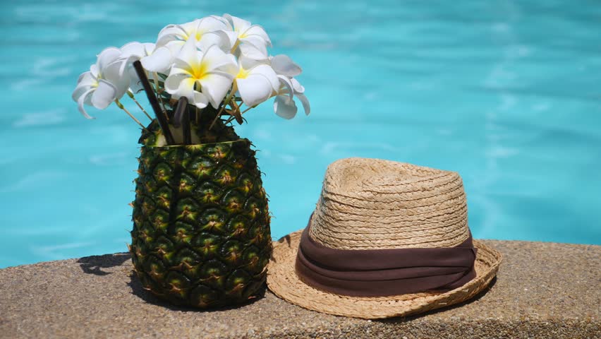 Tropical Pineapple Cocktail And Summer Straw Hat At Swimming Pool. Vacation Concept.