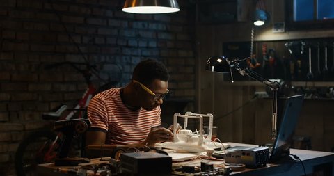 Slow motion shot of a young man repairing a drone in a garage