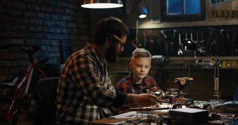 Medium shot of a father and son repairing a drone in a garage