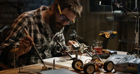 Slow motion shot of a man soldering drone in a garage
