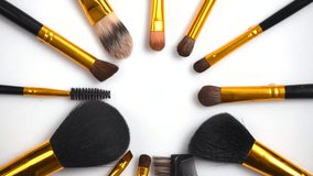 Make-up Brushes set rotated over white background. Various Professional makeup brush rotation on white in studio. Make up artist tools. Flatlay, top view. Turn around. 4K UHD video