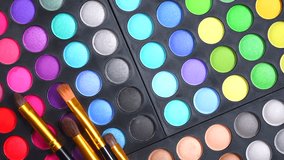 Makeup set, make-up palette and brushes. Professional multicolour make up eyeshadows palette, bright vivid colors and tints of eye shadows set. Rotated background. Makeup artist tools. 4K UHD video