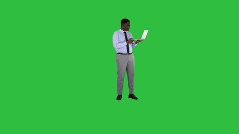 Cheerful successful young African American manager with laptop having video conference call with business partners on a Green Screen, Chroma Key.