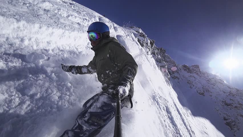 Person snowboarder snowboarding down slope closeup with gopro view white powder snow - winter extreme sports background