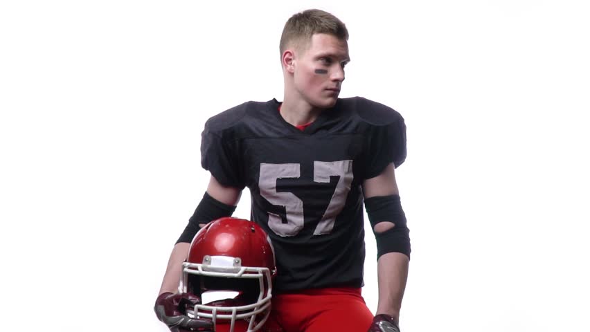 Young man with eye black and full football uniform, poses in the studio