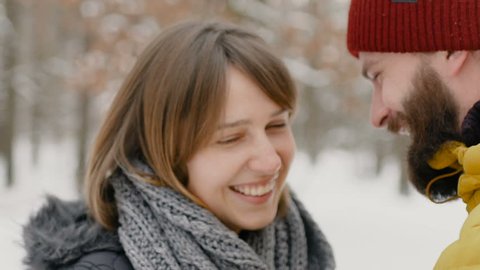 Young happy couple in the winter forest look at each other and smile