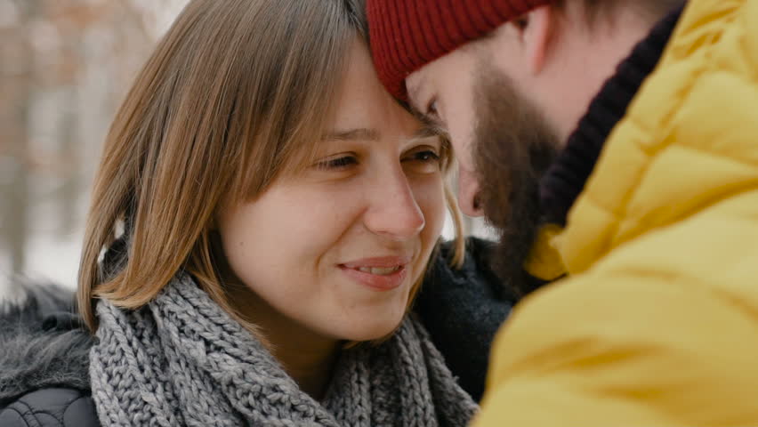 Young happy couple in the winter forest look at each other and smile
